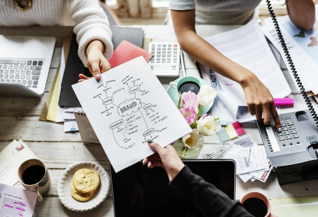 how strong branding will have a huge impact on your business 1 colleagues handing strong branding plan strategy to other