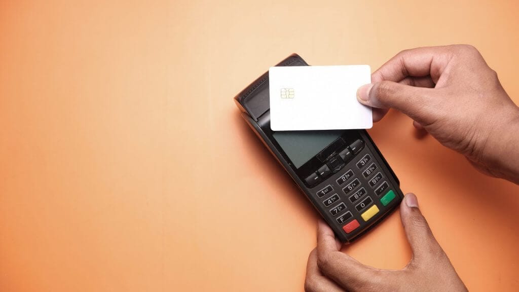 man paying using a card machine on an orange background