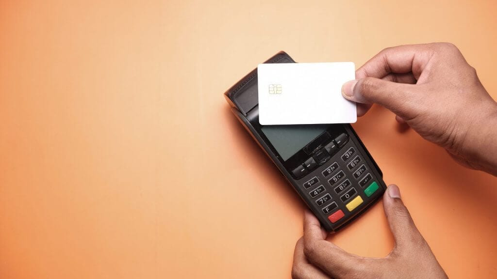 how much does logo design cost in 2022? 8 man paying using a card machine on an orange background